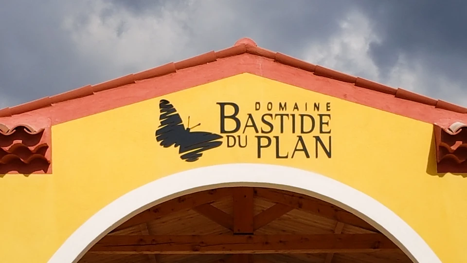 Façade de bâtiment avec enseigne commerciale "Sandwicherie" en lettres cursives dorées sur fond bleu-vert