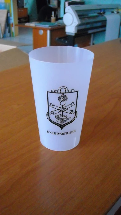 Photographie professionnelle en gros plan d'une mug blanc personnalisé avec logo et inscription graphique imprimés en couleurs vives, présenté seul sur surface neutre. L'objet doit clairement montrer l'impression personnalisée et mettre en évidence la qualité de la réalisation graphique, illustrant les créations d'objets publicitaires de l'imprimerie.